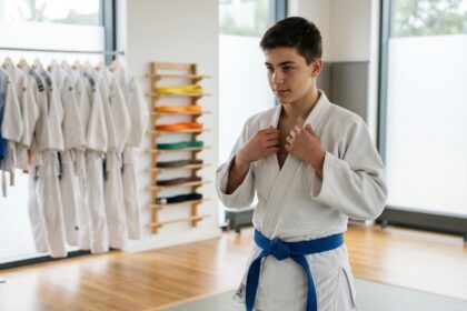 Jeune homme en judogi blanc ajustant sa veste dans un dojo moderne